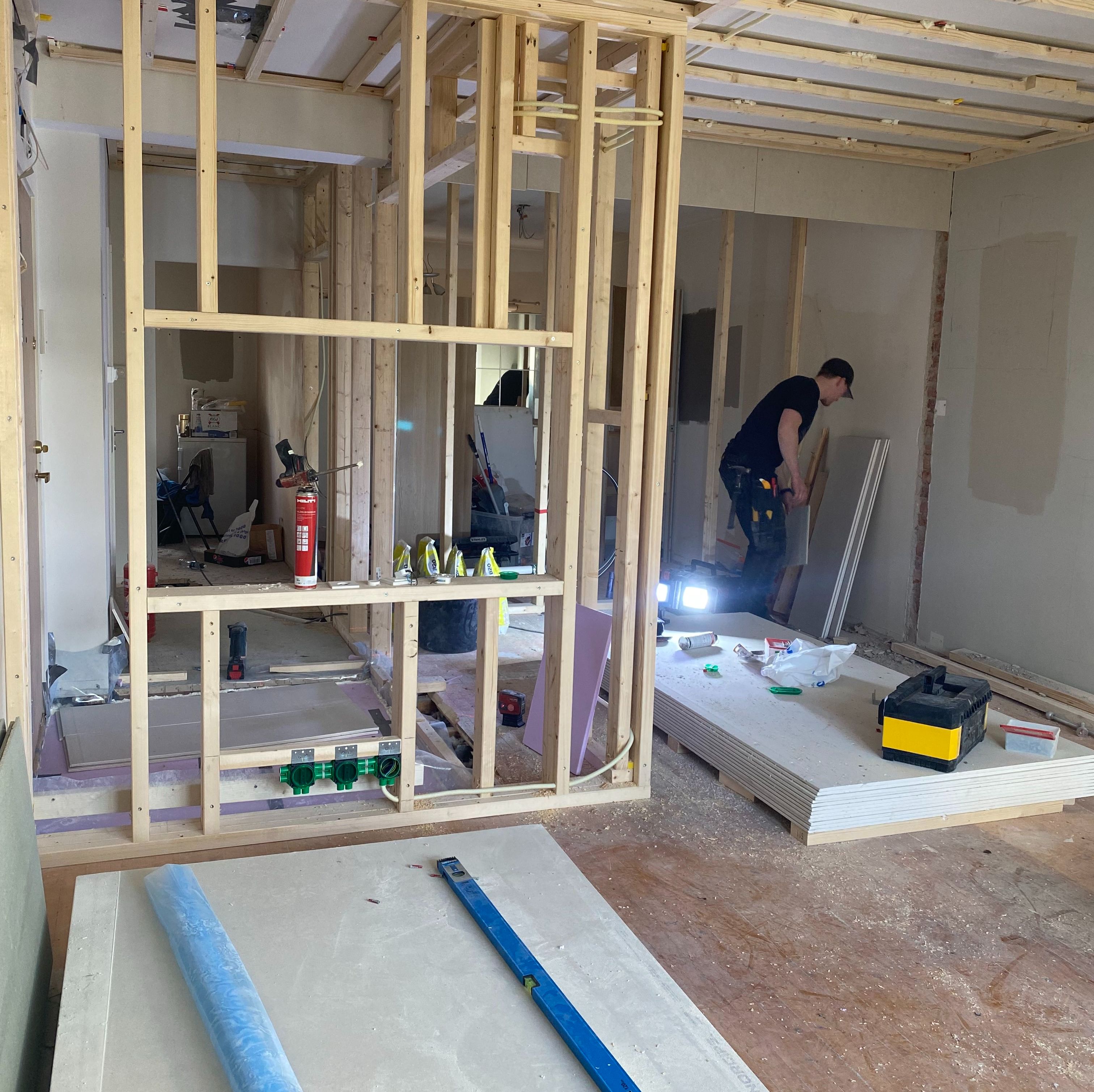 Mann i hjelp og arbeidsklær står i stue under renovering